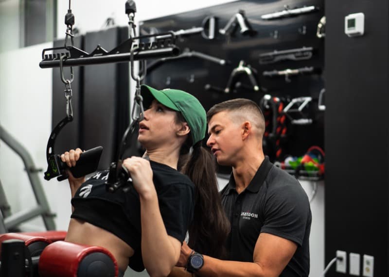 Trainer coaching female client on lat pulldown machine at Arzadon Fitness Toronto