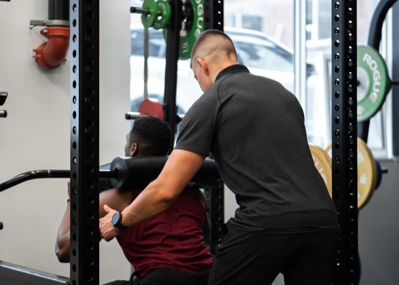 Trainer coaching client during barbell squat at Arzadon Fitness Toronto